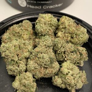 Close-up of Head Cracker Flower cannabis buds, showcasing dense, frosty trichomes, vibrant green hues, and hints of orange pistils, highlighting its potency and premium quality