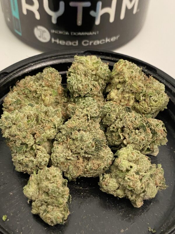 Close-up of Head Cracker Flower cannabis buds, showcasing dense, frosty trichomes, vibrant green hues, and hints of orange pistils, highlighting its potency and premium quality